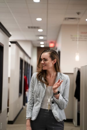 woman smiling and waving while walking in office