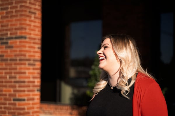 woman with blonde hair looking to the left and laughing