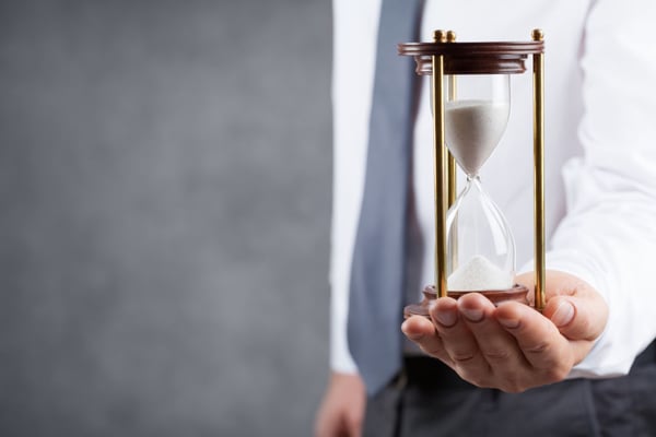  Businessman holding hourglass in his hand. Deadline and time management concept.
