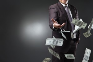 Handsome young man throwing money over dark background