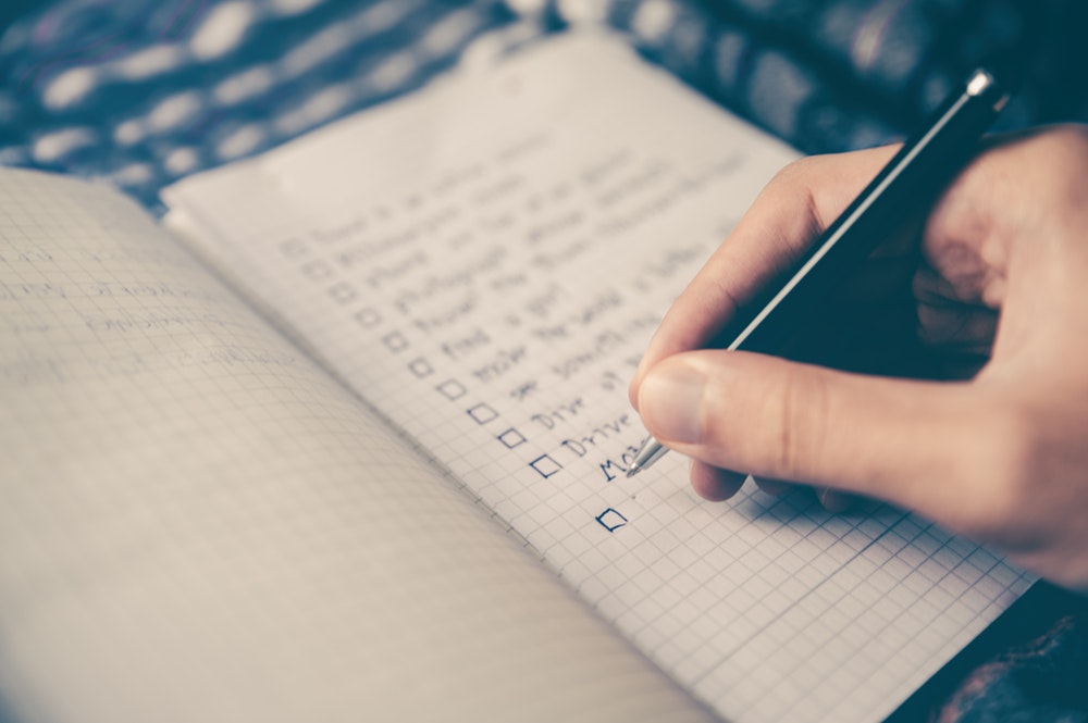 person making a list in a grid notebook