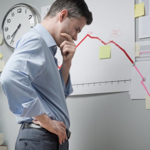 man looking disappointed in front of a negative growth chart