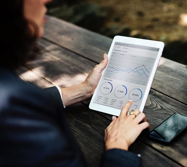 woman holding an ipad with charts and graphs