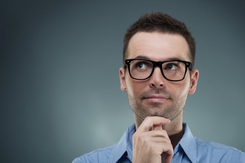 man with black glasses standing with his hand under chin, looking up to the left