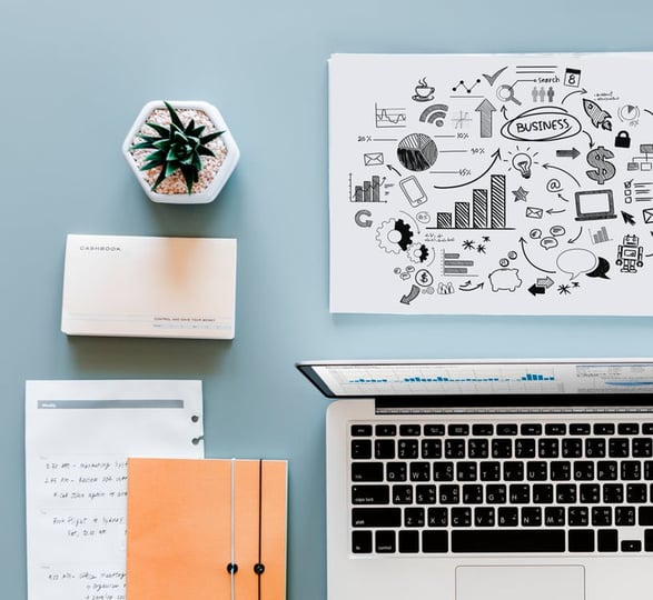 view of a workspace with a laptop, notebooks, growth chart, and plant