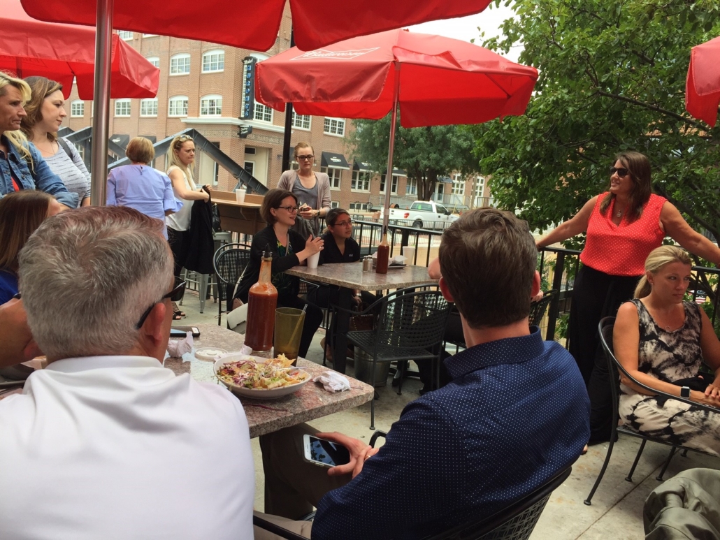 members enjoying tacos at tables under red umbrellas